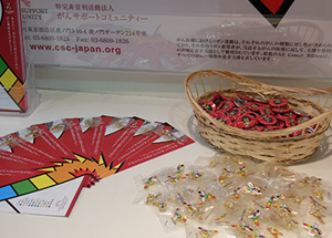 ©Cancer Support Community Japan A cancer prevention leaflet and a rainbow ribbon badge